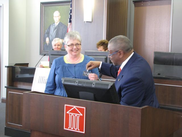 M. Carol Pope received a new name badge from outgoing IJA President Lewis Nixon