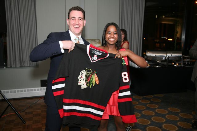 Kenya Jenkins-Wright presents Christopher Niro with the Blackhawks jersey he won in the raffle.