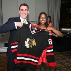 Kenya Jenkins-Wright presents Christopher Niro with the Blackhawks jersey he won in the raffle.
